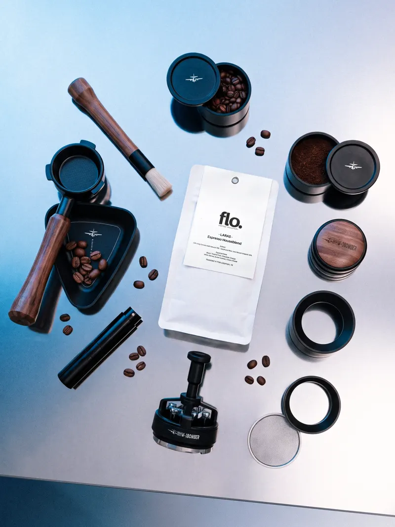 Espresso tools and roasted beans laid out around a flo. espresso blend pouch.