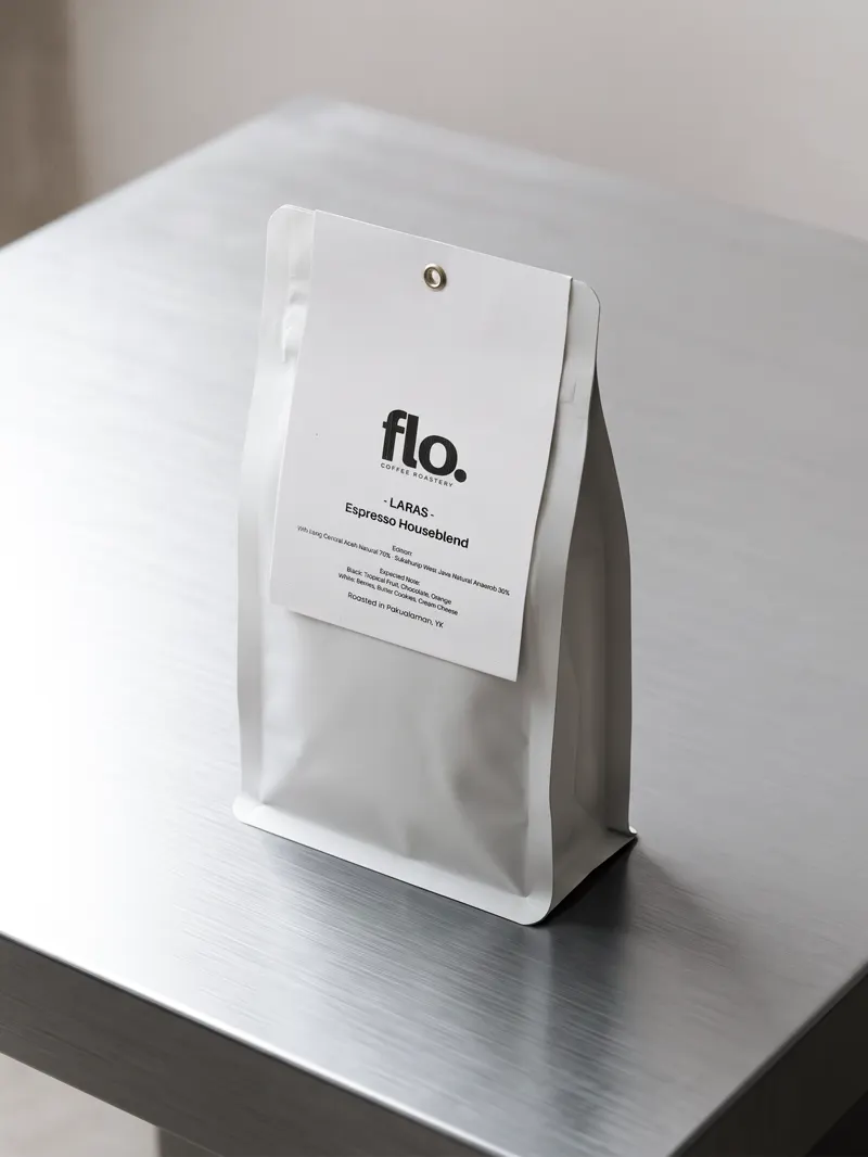 A flo. espresso blend pouch standing on a brushed-steel counter.