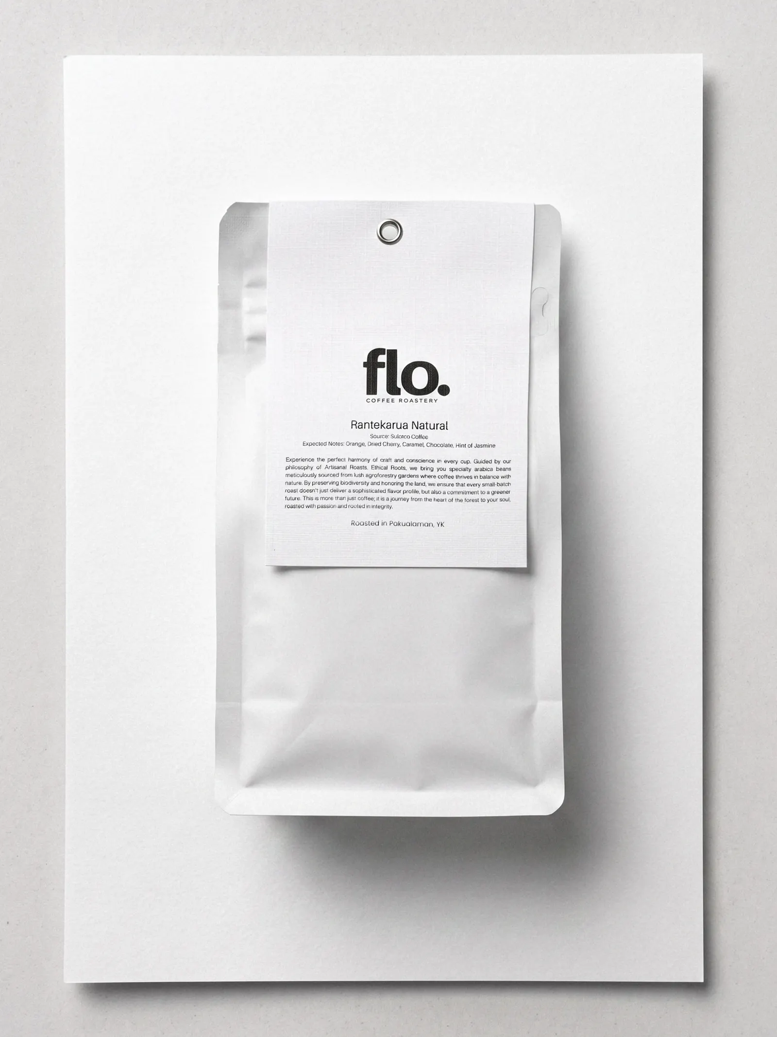 Top-down studio photo of a white flo. coffee bag labelled Rantekarua Natural on textured white paper.